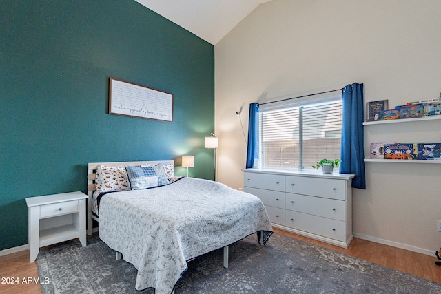 bedroom featuring vaulted ceiling, baseboards, and wood finished floors