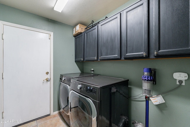 laundry area featuring separate washer and dryer, light tile patterned floors, and cabinet space