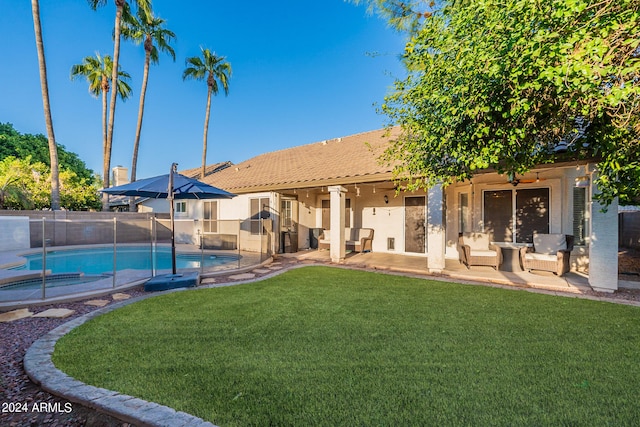 back of property with a swimming pool with hot tub, a patio area, a yard, and ceiling fan