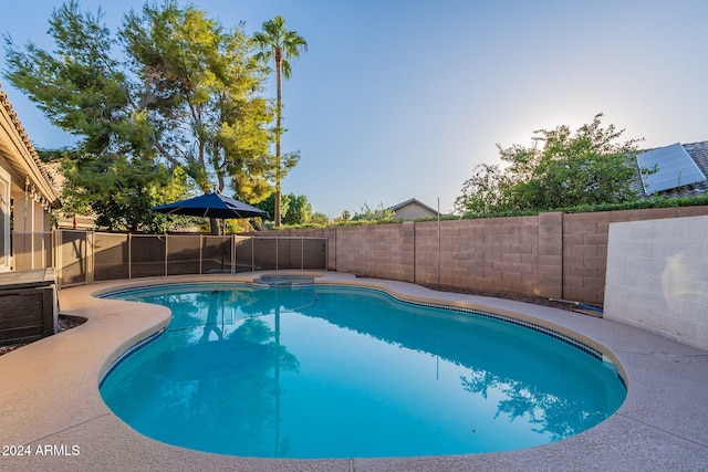 view of swimming pool featuring a pool with connected hot tub and a fenced backyard