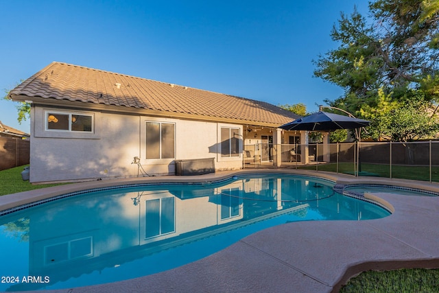 view of swimming pool featuring a patio area, a pool with connected hot tub, and fence