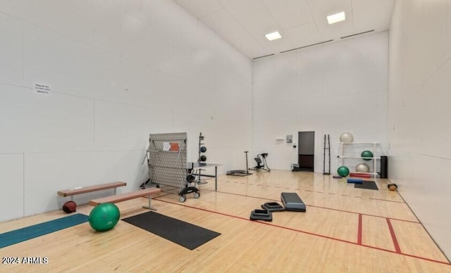 workout room featuring hardwood / wood-style floors and a towering ceiling