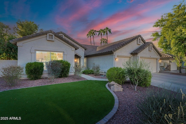 view of front of home with an attached garage, stucco siding, concrete driveway, a front lawn, and a tiled roof