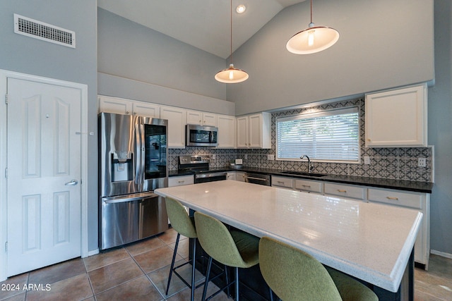 kitchen with tasteful backsplash, visible vents, dark tile patterned floors, stainless steel appliances, and a sink