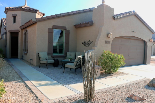 view of side of home with a patio area, a tiled roof, an attached garage, and stucco siding