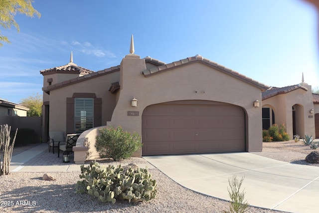 mediterranean / spanish-style house with driveway, an attached garage, a tile roof, and stucco siding