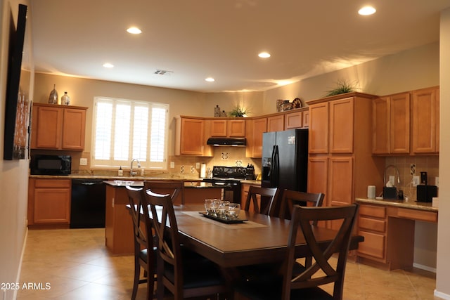 kitchen featuring a kitchen island, tasteful backsplash, sink, a breakfast bar area, and black appliances