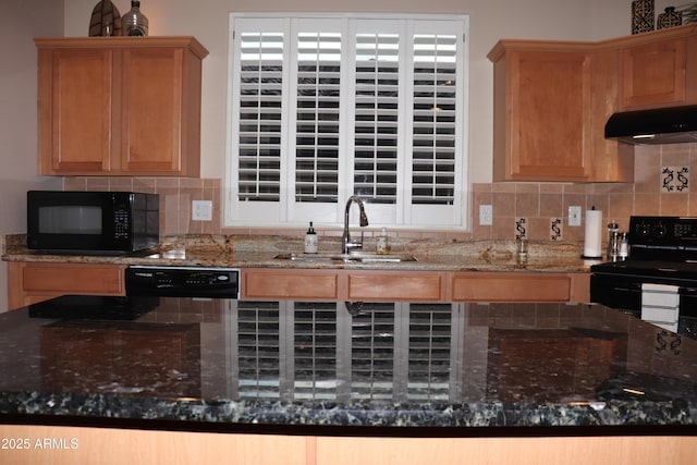 kitchen with tasteful backsplash, a sink, dark stone countertops, under cabinet range hood, and black appliances