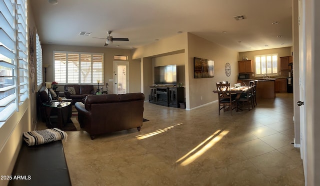 living room featuring a ceiling fan, visible vents, baseboards, and light tile patterned floors