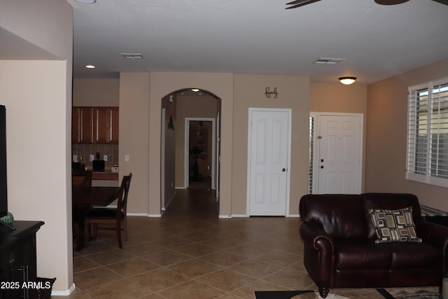 tiled living area with visible vents, arched walkways, and baseboards