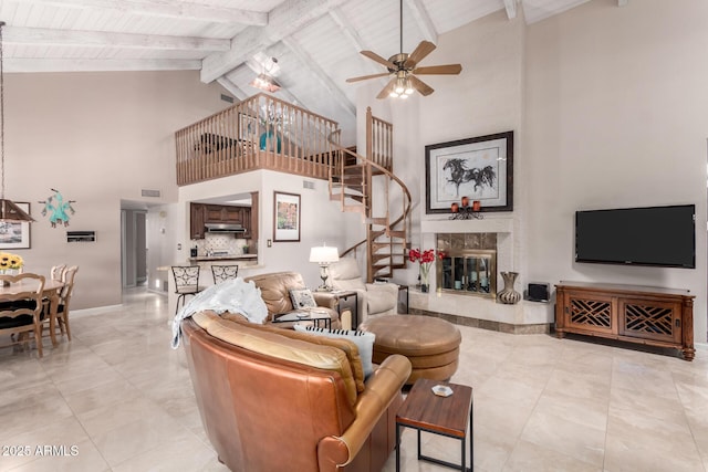 living room with a ceiling fan, visible vents, vaulted ceiling with beams, a high end fireplace, and stairs