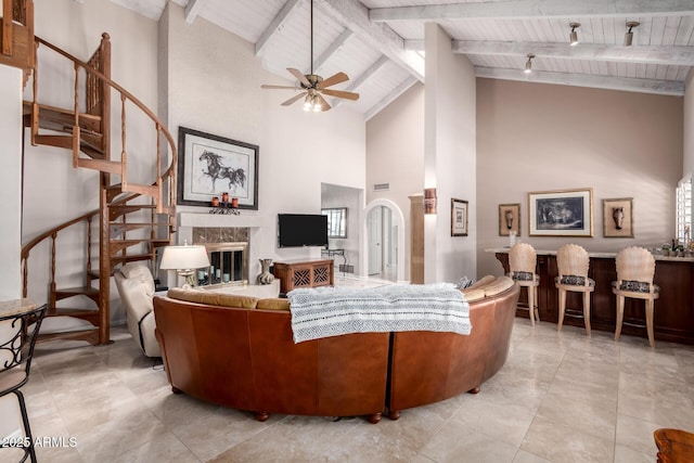 living room with vaulted ceiling with beams, arched walkways, a high end fireplace, stairs, and wood ceiling