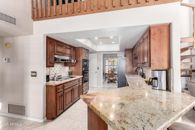 kitchen with visible vents, black appliances, a sink, a tray ceiling, and under cabinet range hood