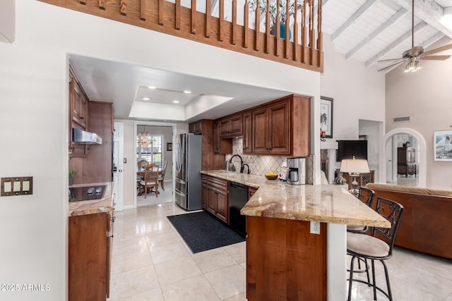 kitchen featuring open floor plan, a breakfast bar area, a peninsula, black appliances, and a sink