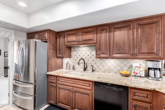 kitchen with light stone countertops, a sink, stainless steel fridge, dishwasher, and tasteful backsplash