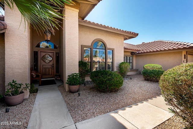 view of exterior entry with stucco siding and a tile roof