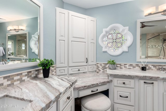 bathroom featuring backsplash, a stall shower, and vanity