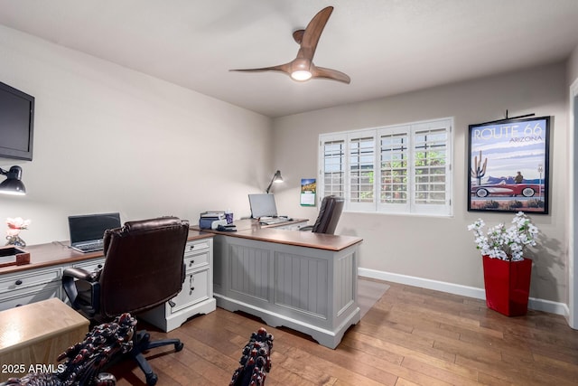 home office with baseboards, hardwood / wood-style floors, and a ceiling fan