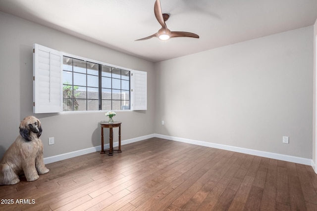 spare room with a ceiling fan, wood finished floors, and baseboards