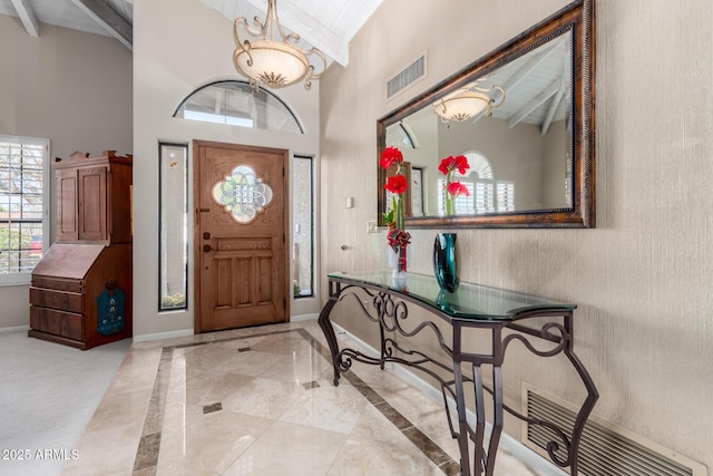 entryway with visible vents, beamed ceiling, high vaulted ceiling, and baseboards