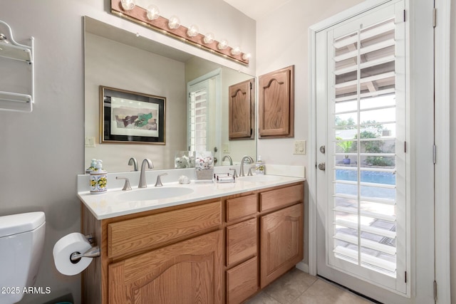 bathroom with a sink, toilet, double vanity, and tile patterned floors