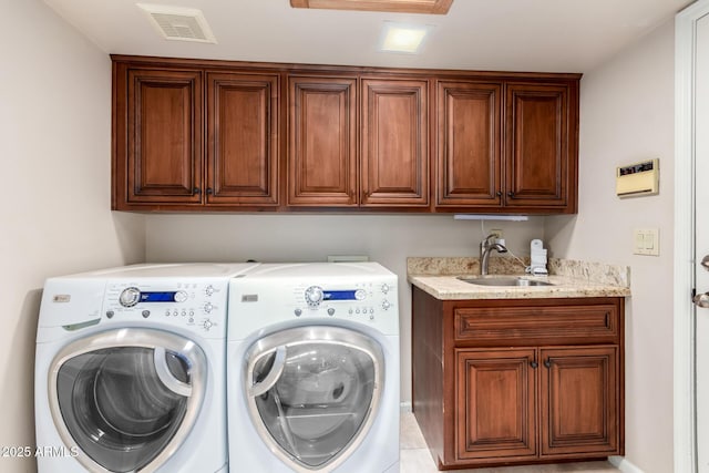 washroom featuring independent washer and dryer, cabinet space, visible vents, and a sink