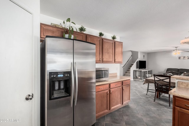 kitchen featuring appliances with stainless steel finishes, open floor plan, light countertops, and brown cabinets