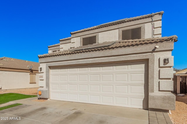 view of front of home with driveway, a tile roof, a garage, and stucco siding