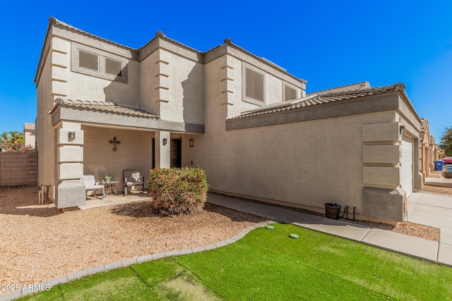 view of front of house featuring a tiled roof, fence, and stucco siding