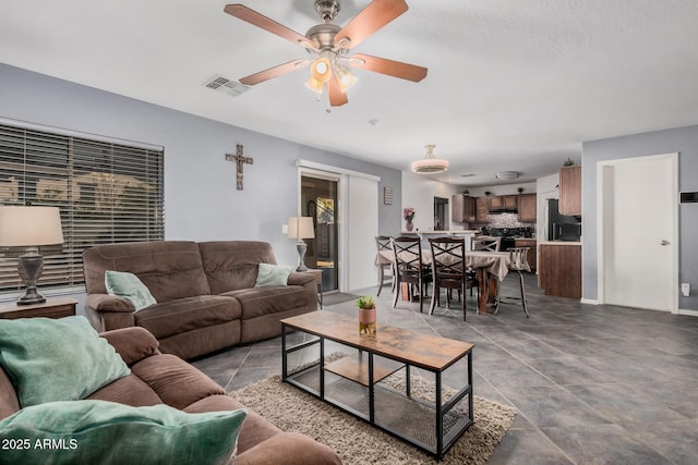 living room with ceiling fan, visible vents, and tile patterned floors