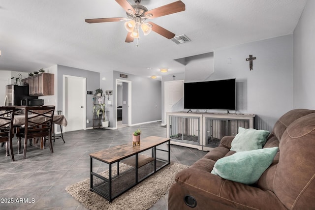 living area with visible vents, ceiling fan, and a textured ceiling