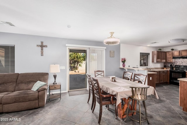 dining space featuring dark tile patterned flooring, visible vents, and baseboards