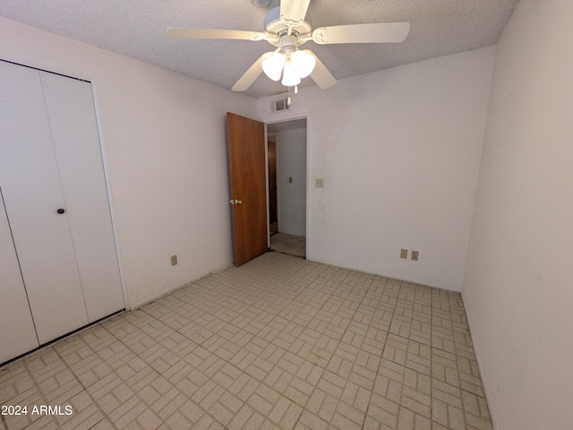 unfurnished bedroom with ceiling fan, a closet, visible vents, and a textured ceiling