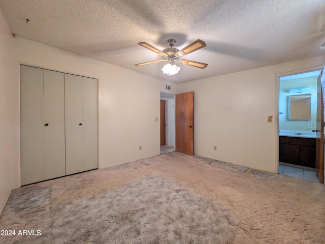 unfurnished bedroom with a textured ceiling, ceiling fan, carpet floors, visible vents, and a closet