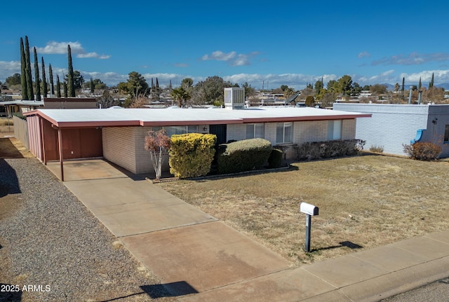 view of front of property featuring a carport, concrete driveway, brick siding, and a front lawn