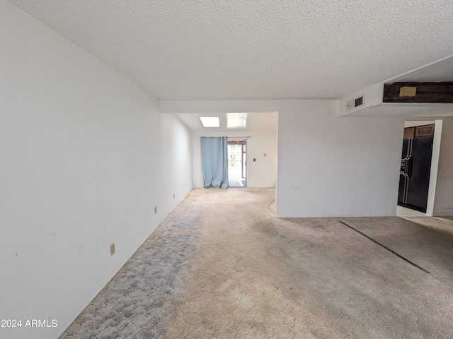 carpeted empty room with visible vents and a textured ceiling