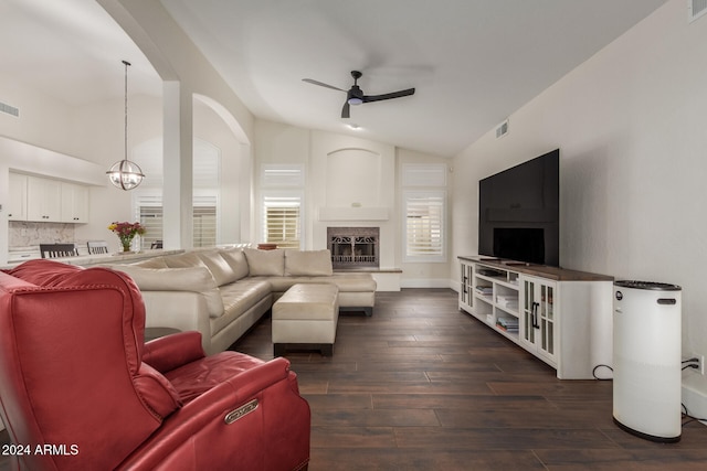 living room with a fireplace, ceiling fan with notable chandelier, dark hardwood / wood-style floors, and vaulted ceiling