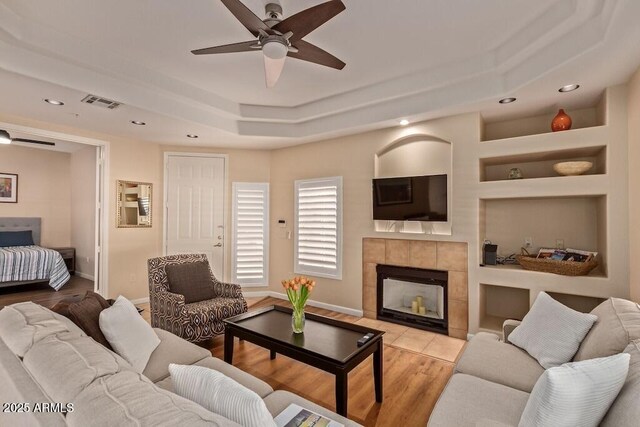 8245 E Bell Rd Unit 133, Scottsdale, AZ 85260 - living area with visible vents, wood finished floors, a raised ceiling, built in shelves, and ceiling fan