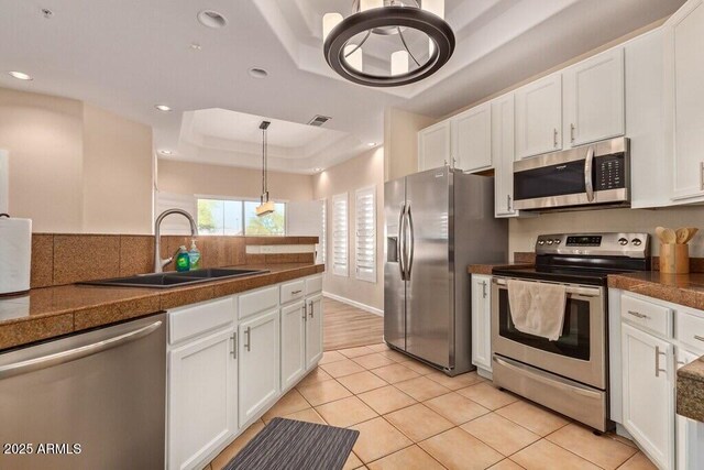 8245 E Bell Rd Unit 133, Scottsdale, AZ 85260 - kitchen featuring tile countertops, white cabinets, appliances with stainless steel finishes, a sink, and a raised ceiling