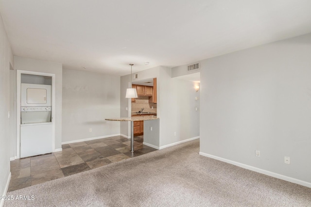 200 E Southern Ave Unit 226, Tempe, AZ 85282 - unfurnished living room with stacked washing machine and dryer, baseboards, dark colored carpet, and a sink