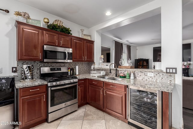 kitchen with beverage cooler, a sink, tasteful backsplash, stainless steel appliances, and a peninsula