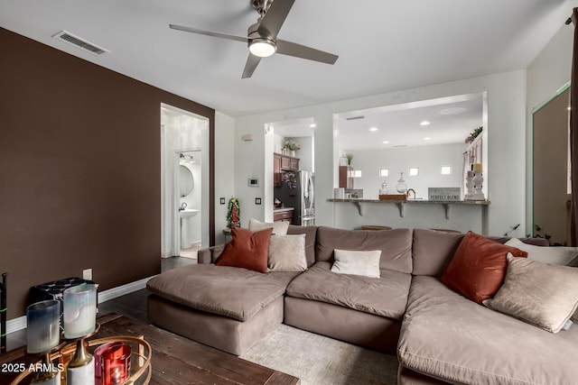 living room with baseboards, wood finished floors, visible vents, and ceiling fan