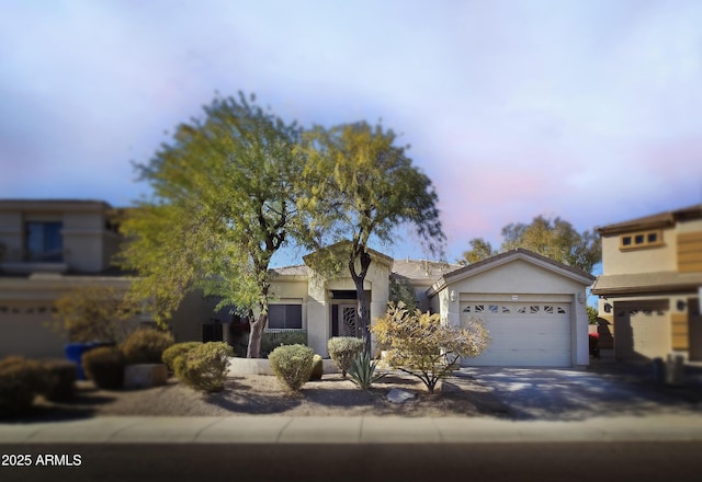 view of front of house featuring driveway, an attached garage, and stucco siding