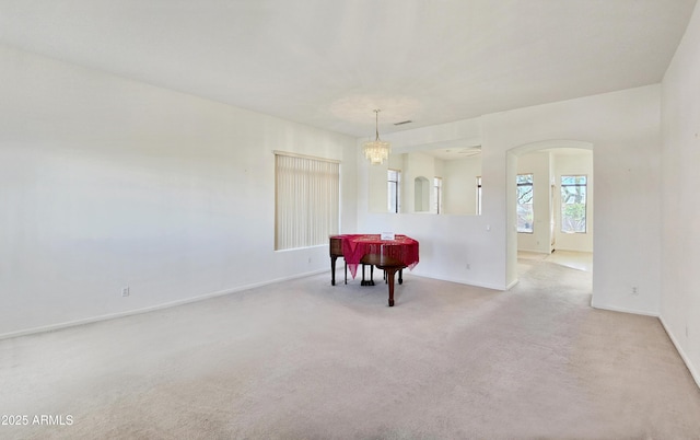 carpeted dining area featuring baseboards, arched walkways, and a chandelier