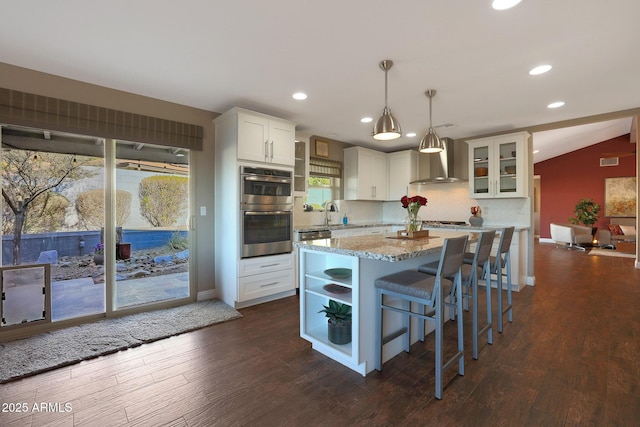 kitchen with white cabinetry, wall chimney range hood, pendant lighting, lofted ceiling, and appliances with stainless steel finishes