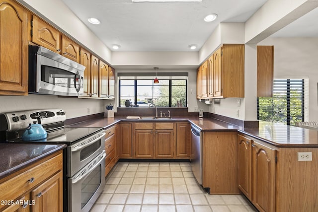 kitchen with kitchen peninsula, a wealth of natural light, sink, and stainless steel appliances