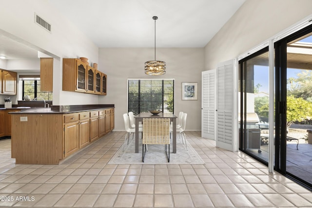 tiled dining space featuring a notable chandelier, a healthy amount of sunlight, and sink