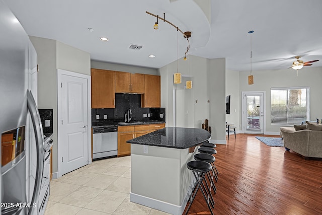 kitchen featuring sink, a center island, a kitchen breakfast bar, pendant lighting, and appliances with stainless steel finishes