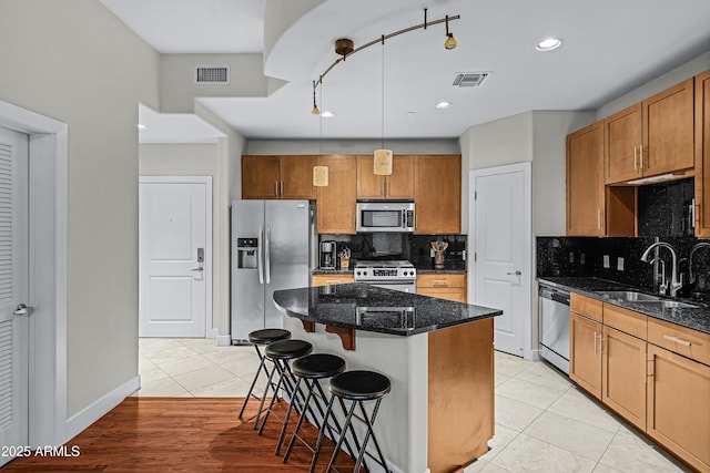 kitchen with appliances with stainless steel finishes, a center island, light tile patterned floors, and hanging light fixtures