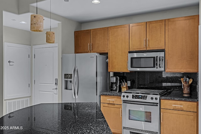 kitchen featuring hanging light fixtures, dark stone countertops, backsplash, and appliances with stainless steel finishes